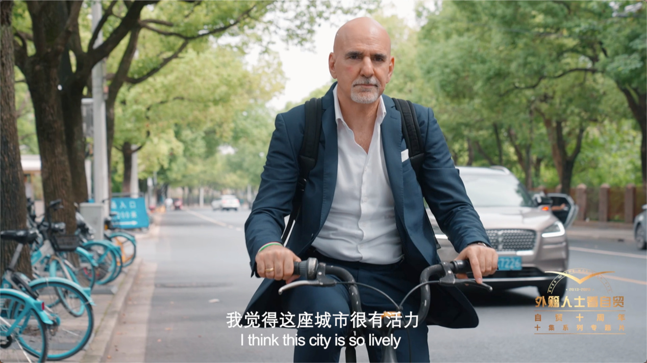 康华特在上海浦东街头骑着共享单车。 “外籍人士看自贸”系列专题片截图