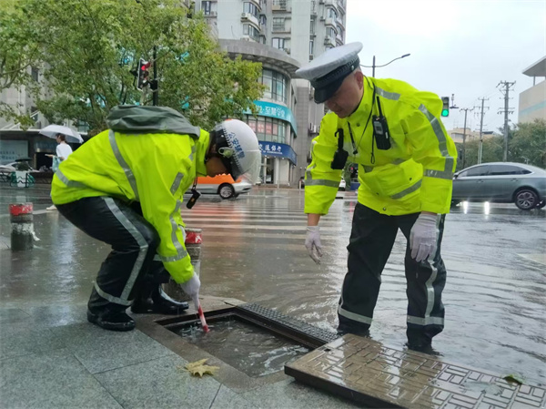 四大队民警苏张灵、辅警王志斌在牡丹江路宝林路积水点对下水道进行清理。