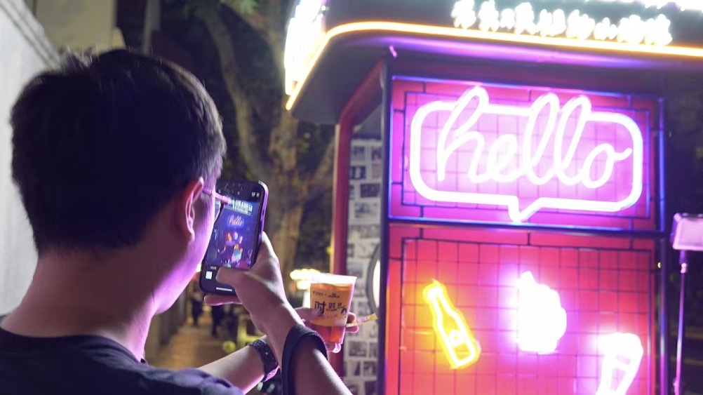 赵先生举着酒杯在“把酒言欢”亭前拍照留念