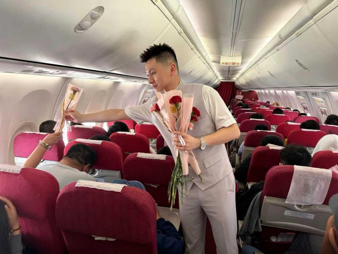 乘务员在为客舱上的母亲献花。人民网记者 龚莎摄